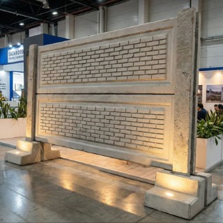 دیوار پیش ساخته بتنی با طرح آجر و پایه‌های فونداسیون H شکل در غرفه نمایشگاه (Precast concrete wall with brick pattern and H-shaped foundation bases at a trade show booth)